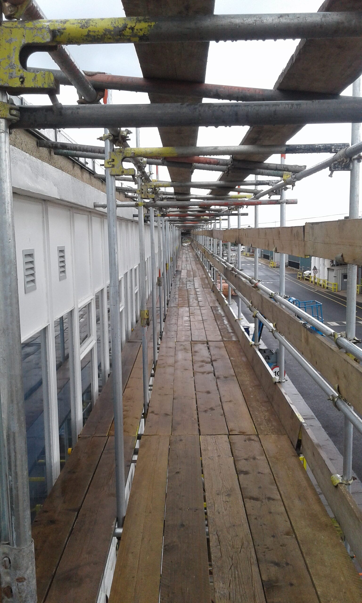 Boarded scaffold walkway with handrails under cover